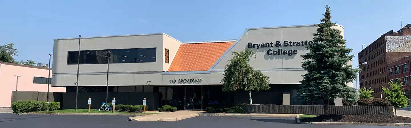 A modern building with a sign reading "Bryant & Stratton College" and the address "180 Broadway" on a sunny day.