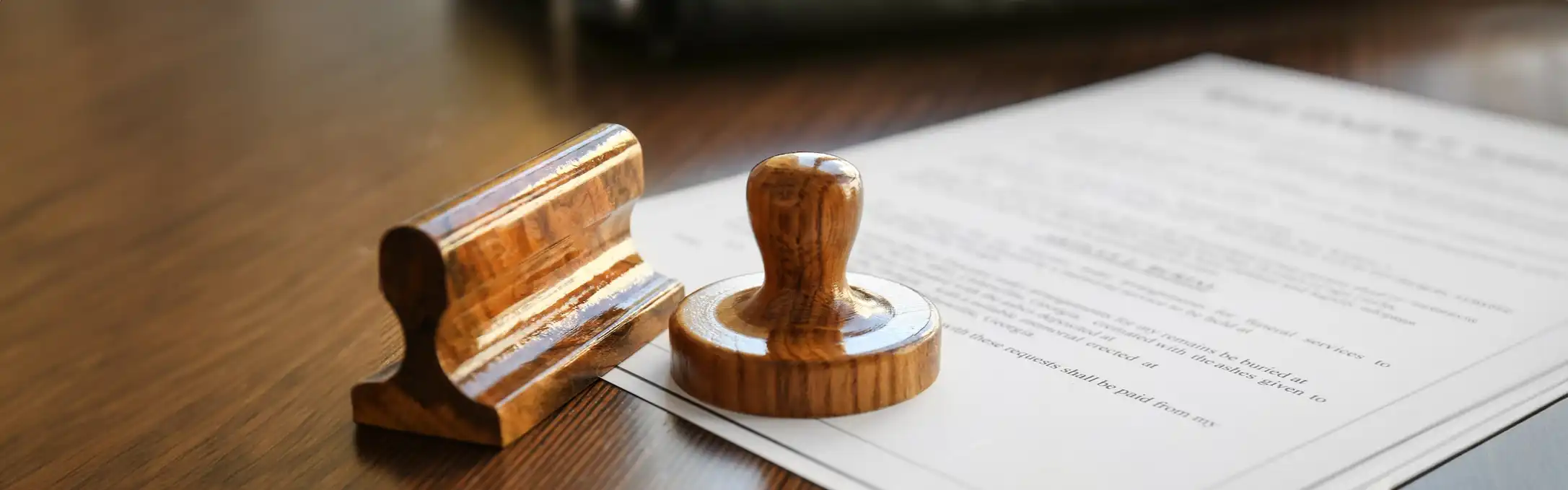 A wooden stamp resting on a document lying on a wooden table.