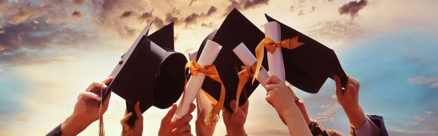 Agroup of hands holding graduation caps and degrees.