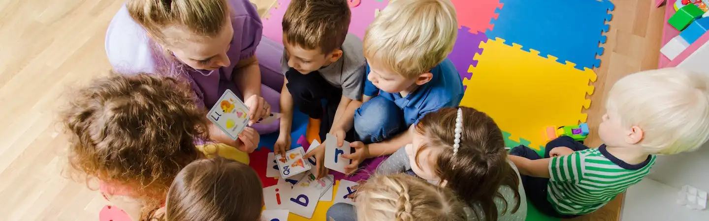 A group of children sitting on the floor with a teacher.