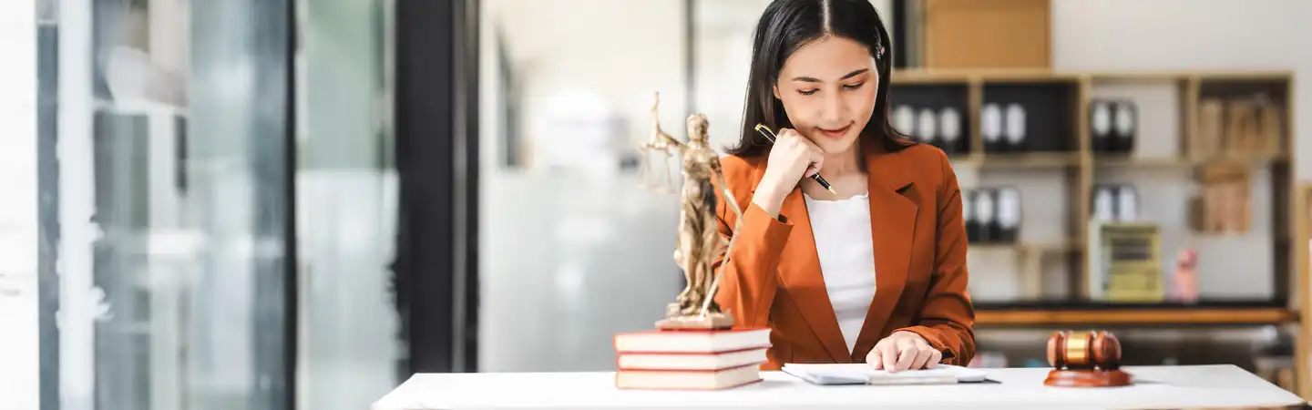 A person sitting at a desk with a statue of justice.