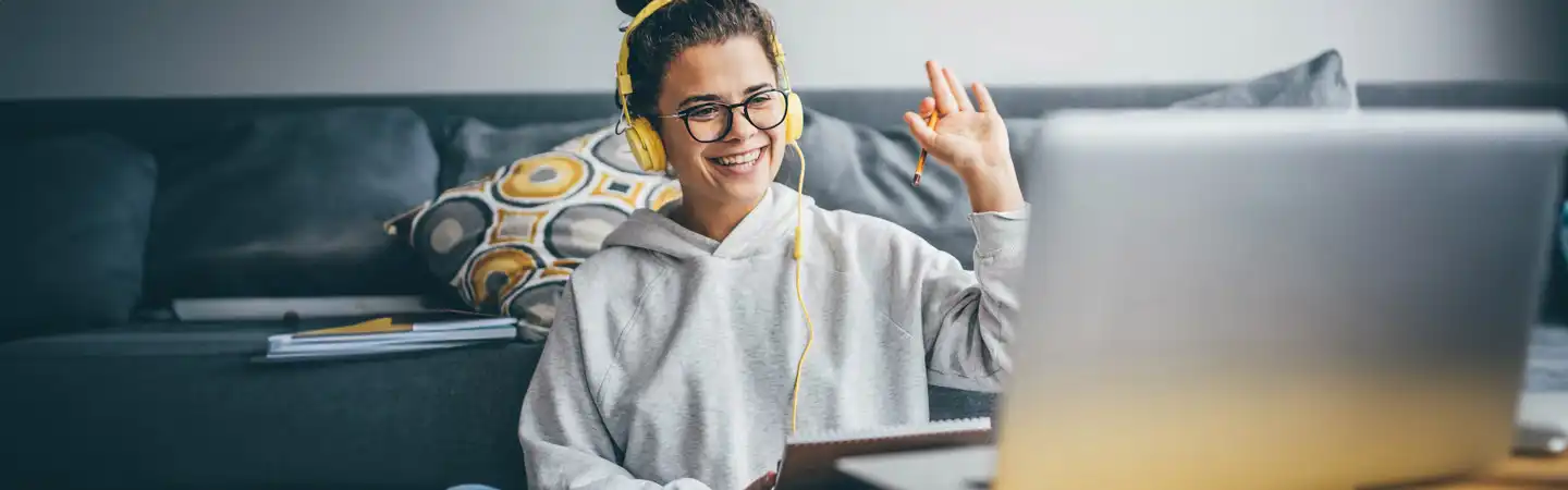 Girl with glasses at home waving to her laptop